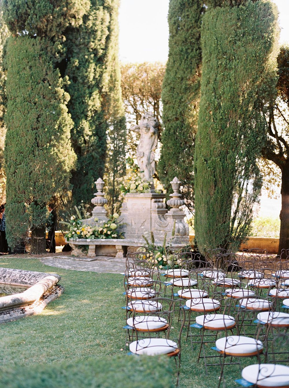 Serene garden wedding at La Foce, featuring chairs and trees as the backdrop for the ceremony.