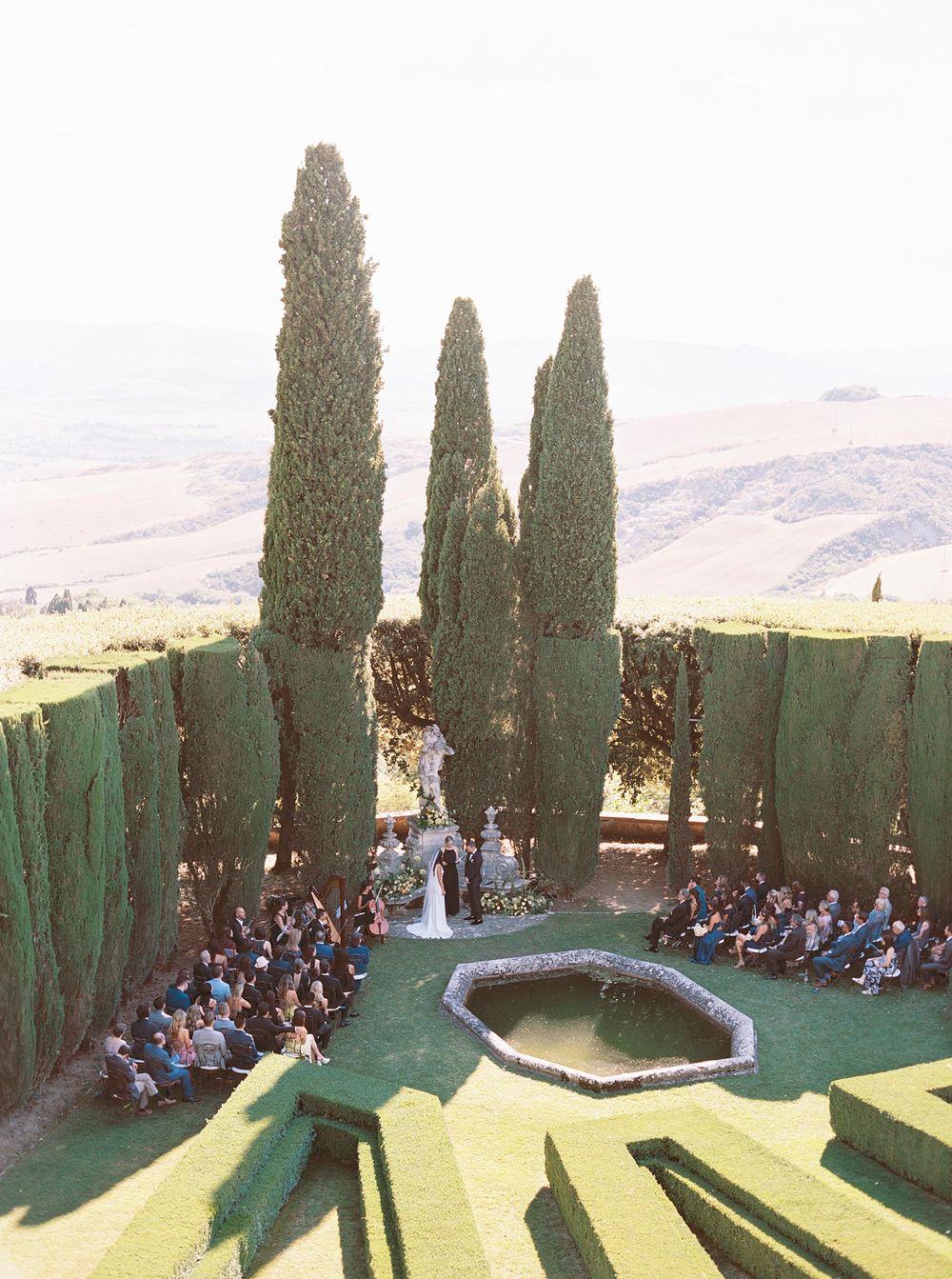 A professional photographer capturing a wedding ceremony in the garden of La Foce, Tuscany.