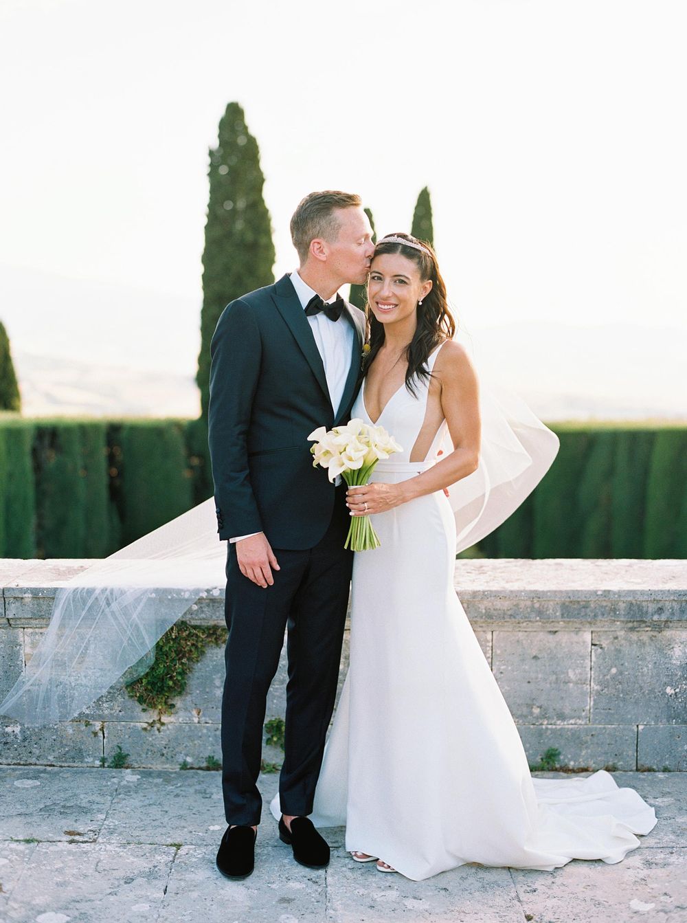 A wedding photographer captures the bride and groom amidst the picturesque garden of La Foce, creating a timeless memory