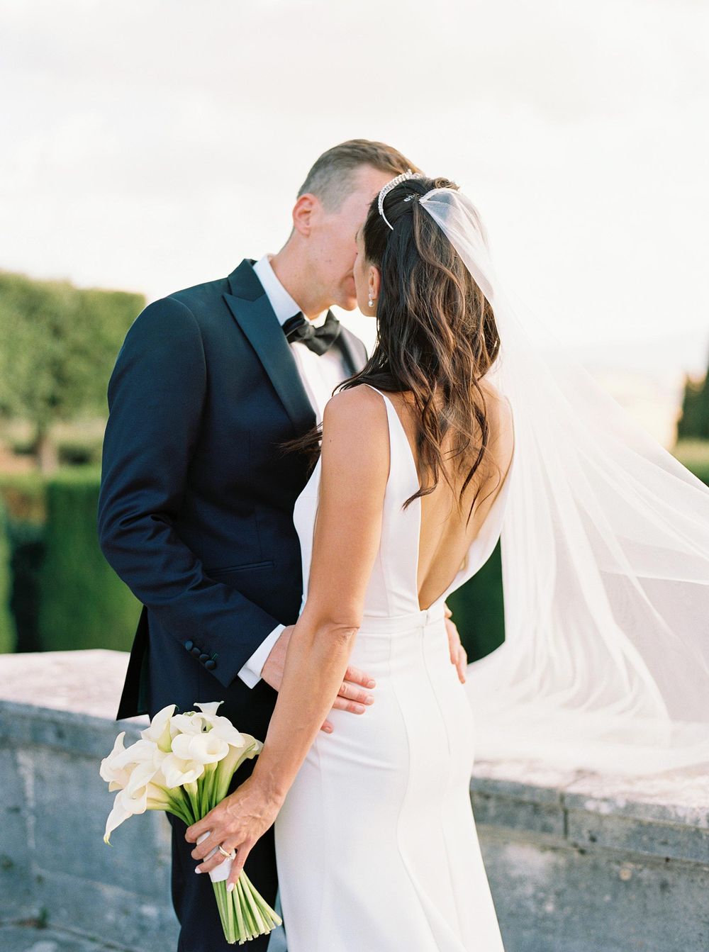 Wedding photographer capturing a romantic moment as the bride and groom share a kiss in La Foce, Italy.
