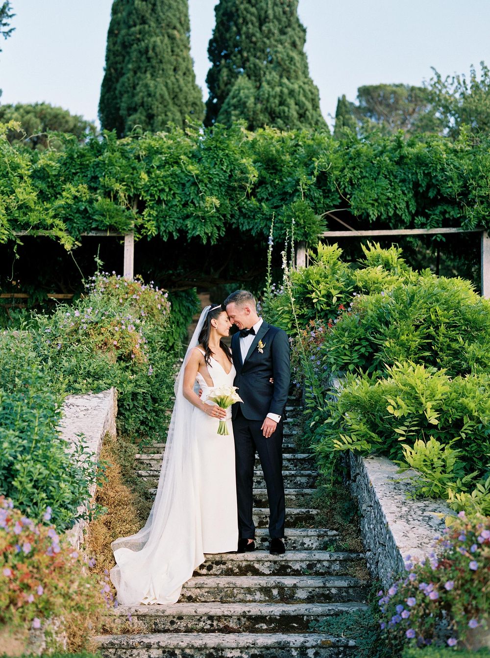 A professional wedding photographer captures a beautiful moment of a bride and groom posing in La Foce, Tuscany.