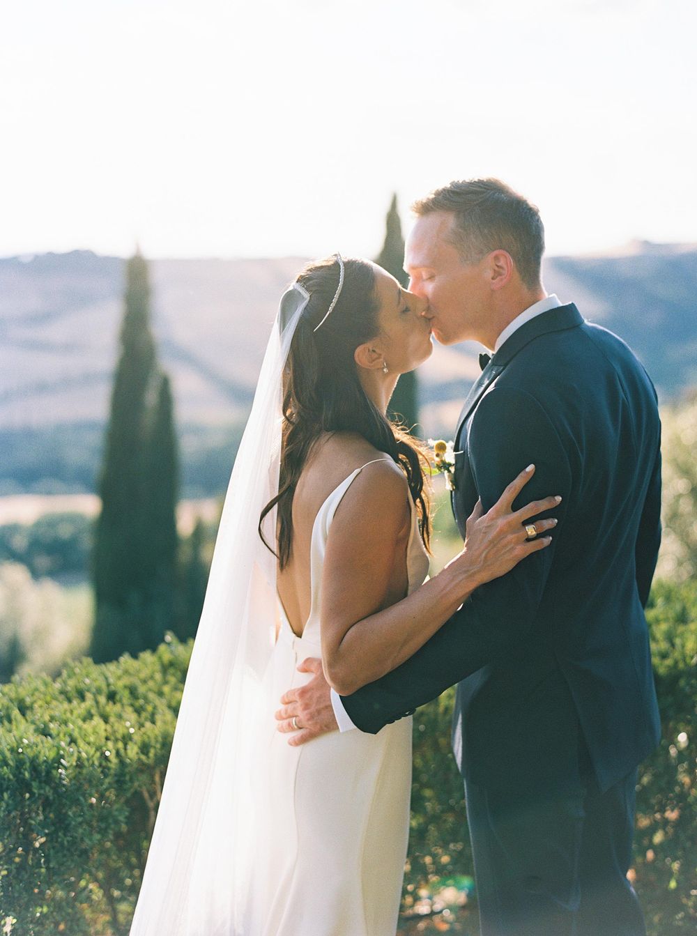 A beautiful bride and groom standing in the picturesque landscape of Tuscany, Italy.