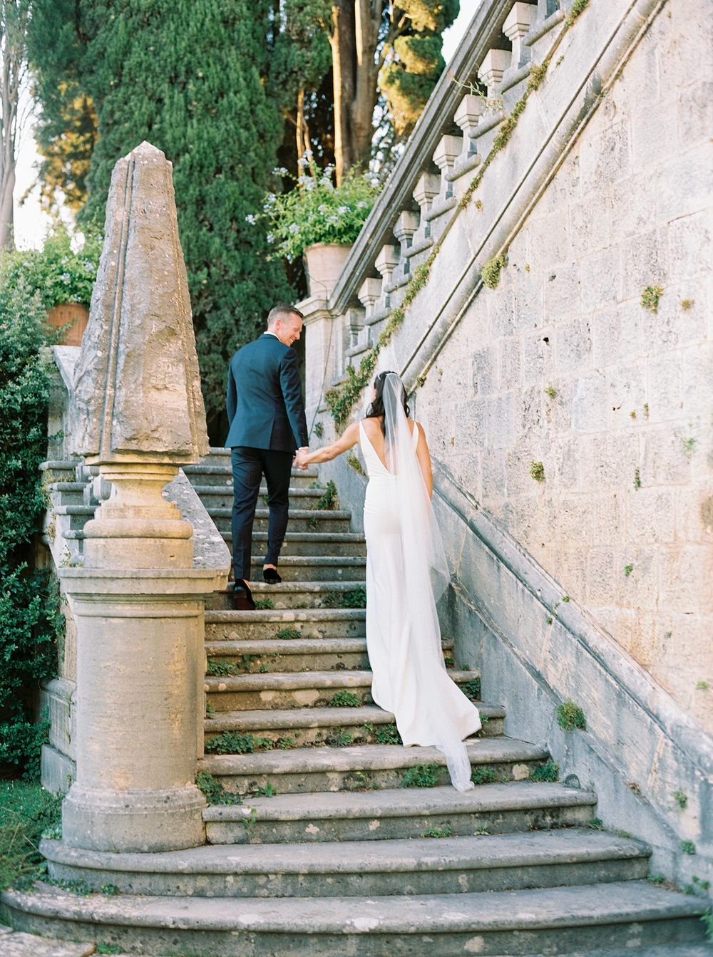 Fine Art Wedding photographer capturing a beautiful moment of bride and groom on a garden staircase in La Foce, Tuscany.