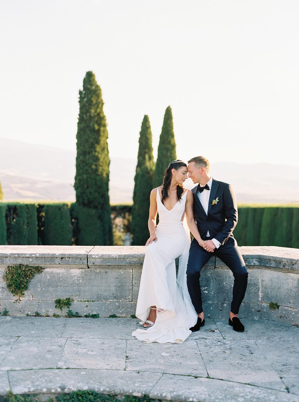 A picturesque wedding in Tuscany, Italy. The bride and groom elegantly posing in the garden of La Foce.