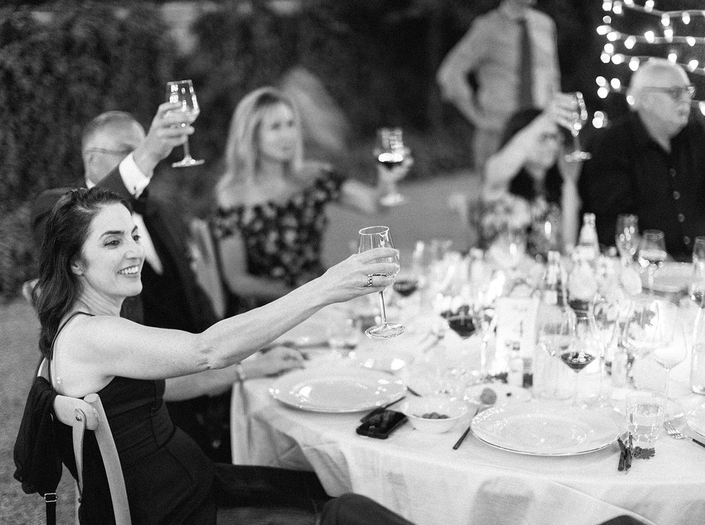 Wedding guests raising glasses at a dinner table in Tuscany.