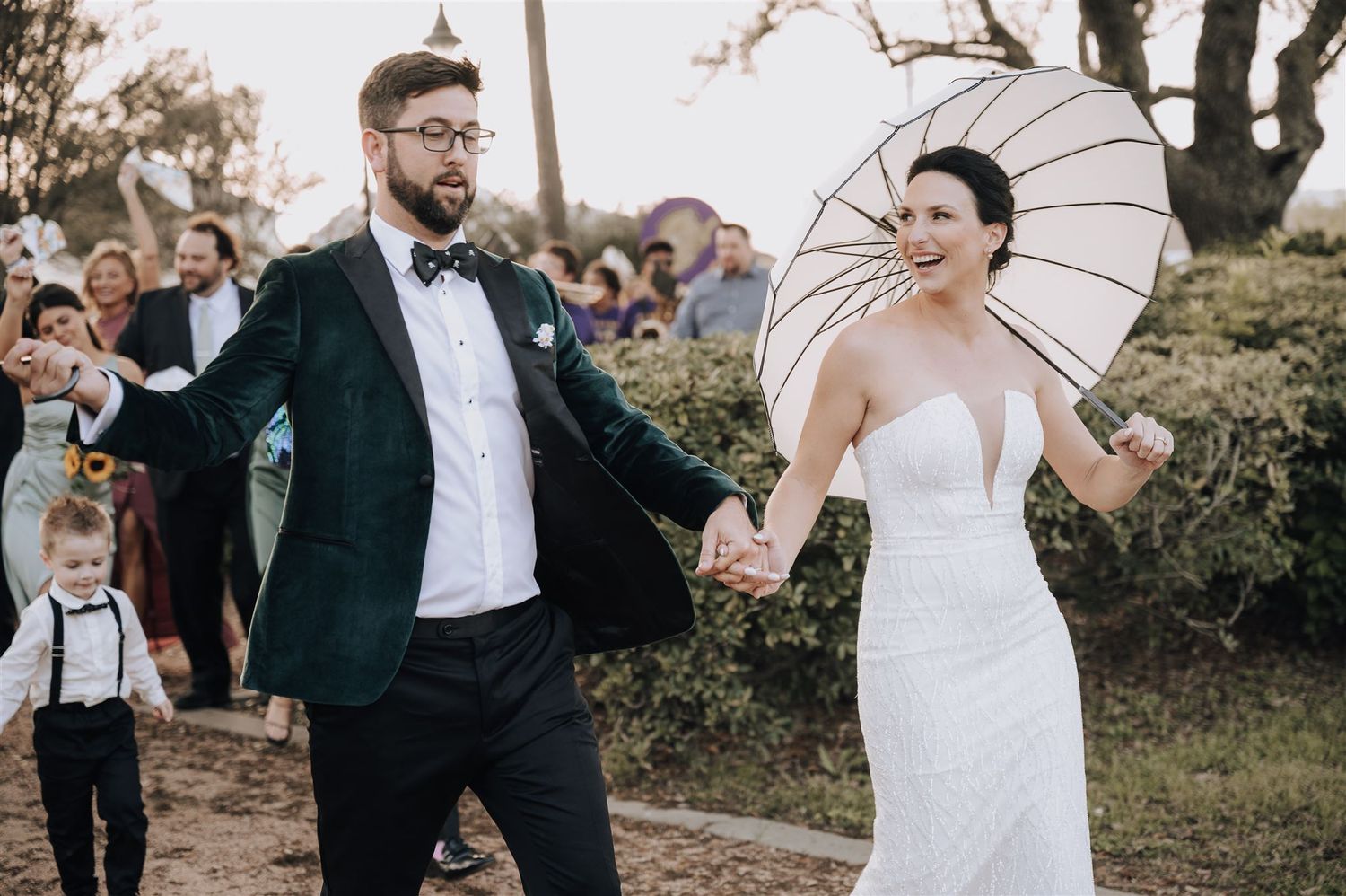 A couple celebrates with parasols during an outdoor wedding ceremony.