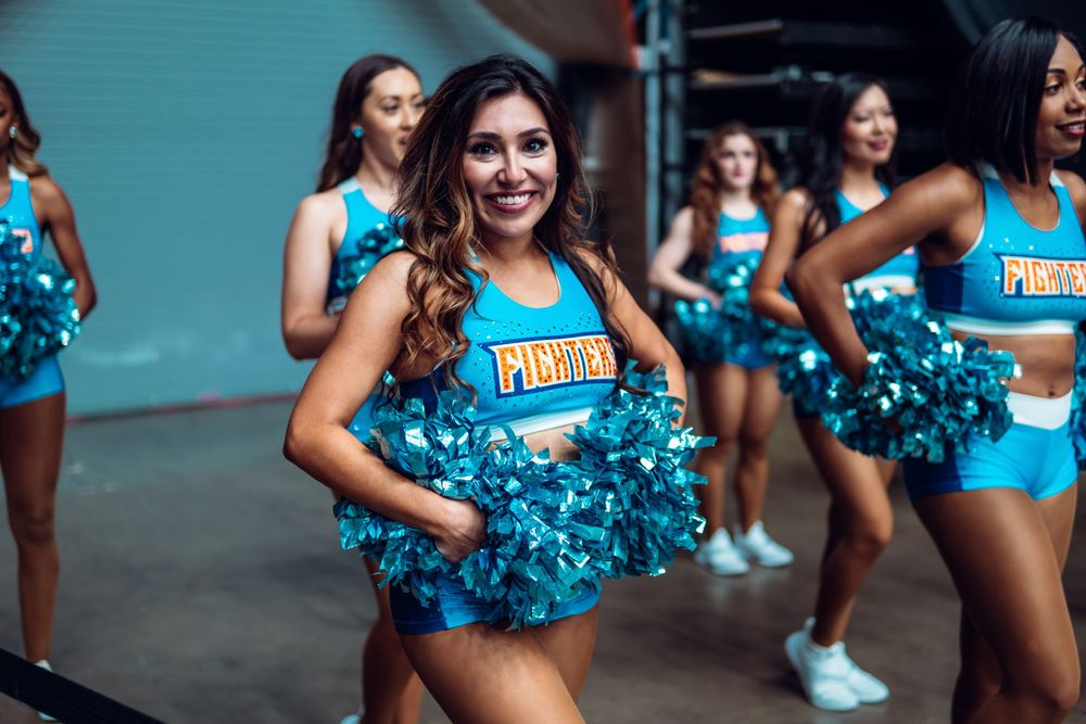 Cheerleaders in turquoise uniforms perform during sports event.
