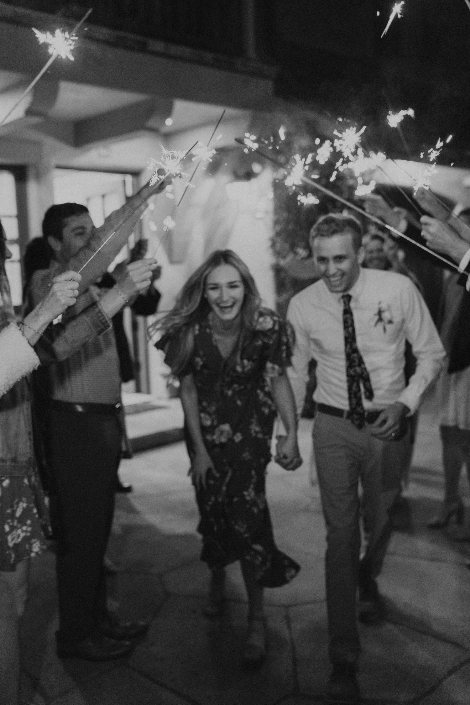 Wedding party celebrating with sparklers at night creating trails of light and joy.
