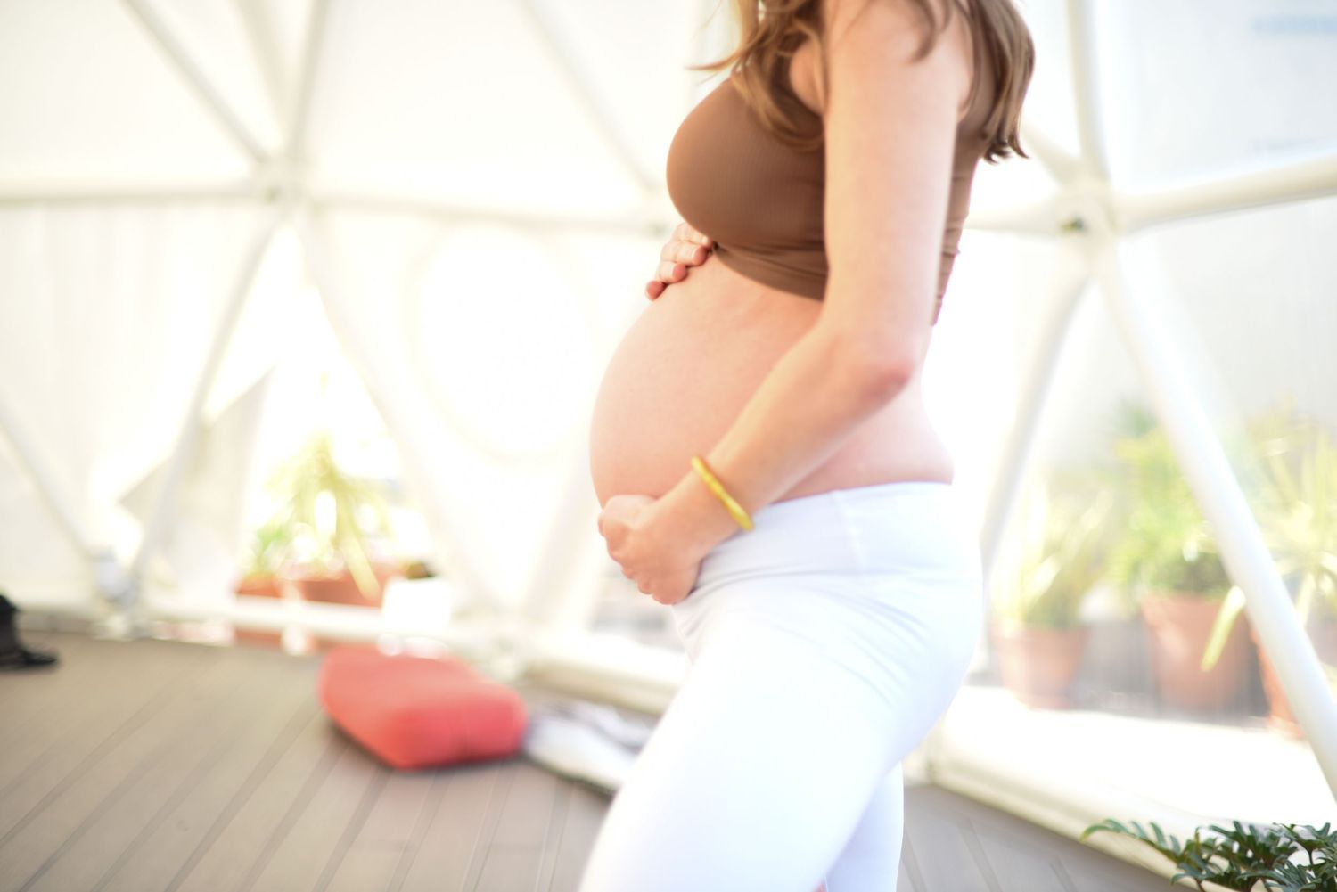 Two people stand against a colorful tiled wall background during a maternity photoshoot.