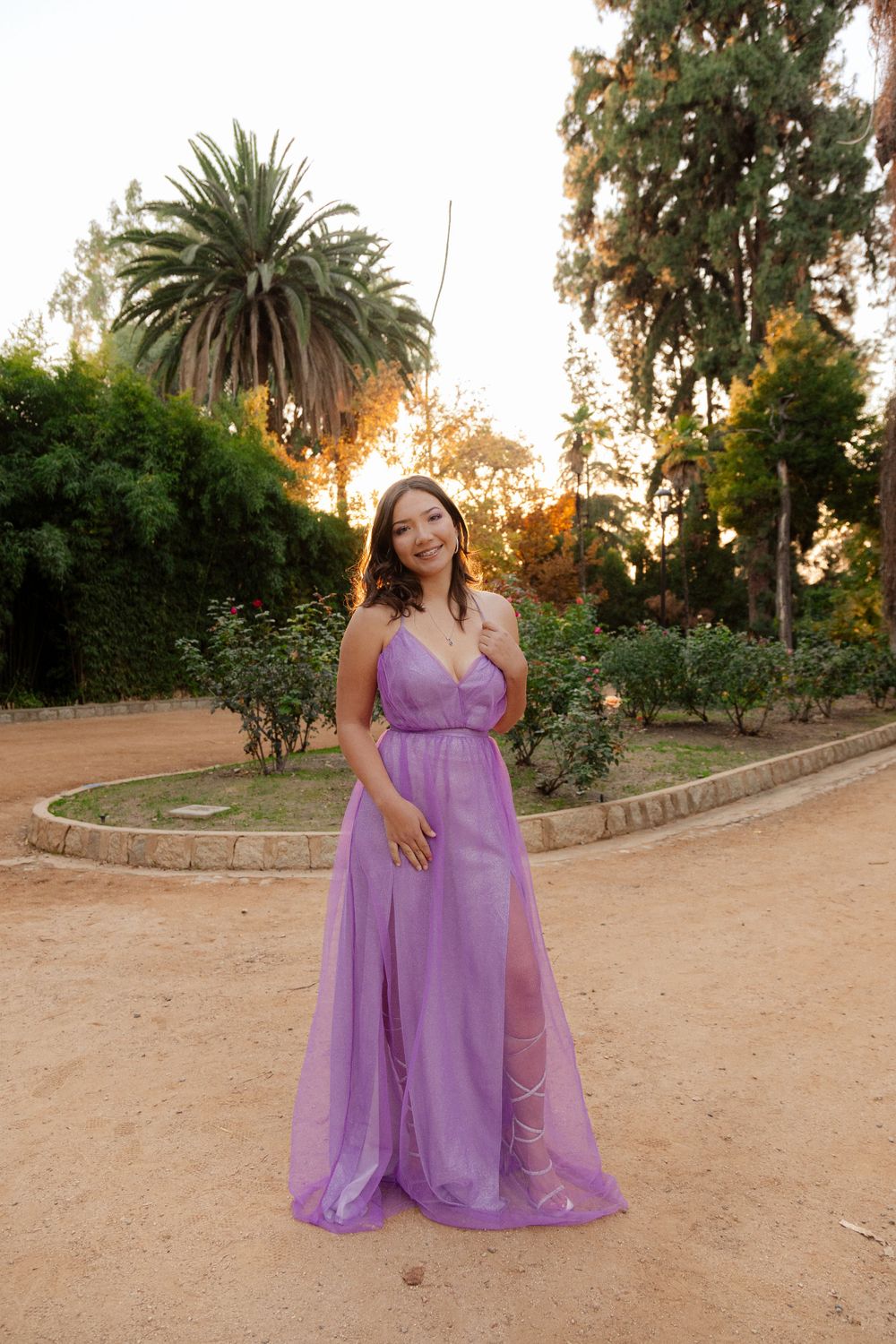 Full-length shot of figure in floor-length purple gown posing in garden path.