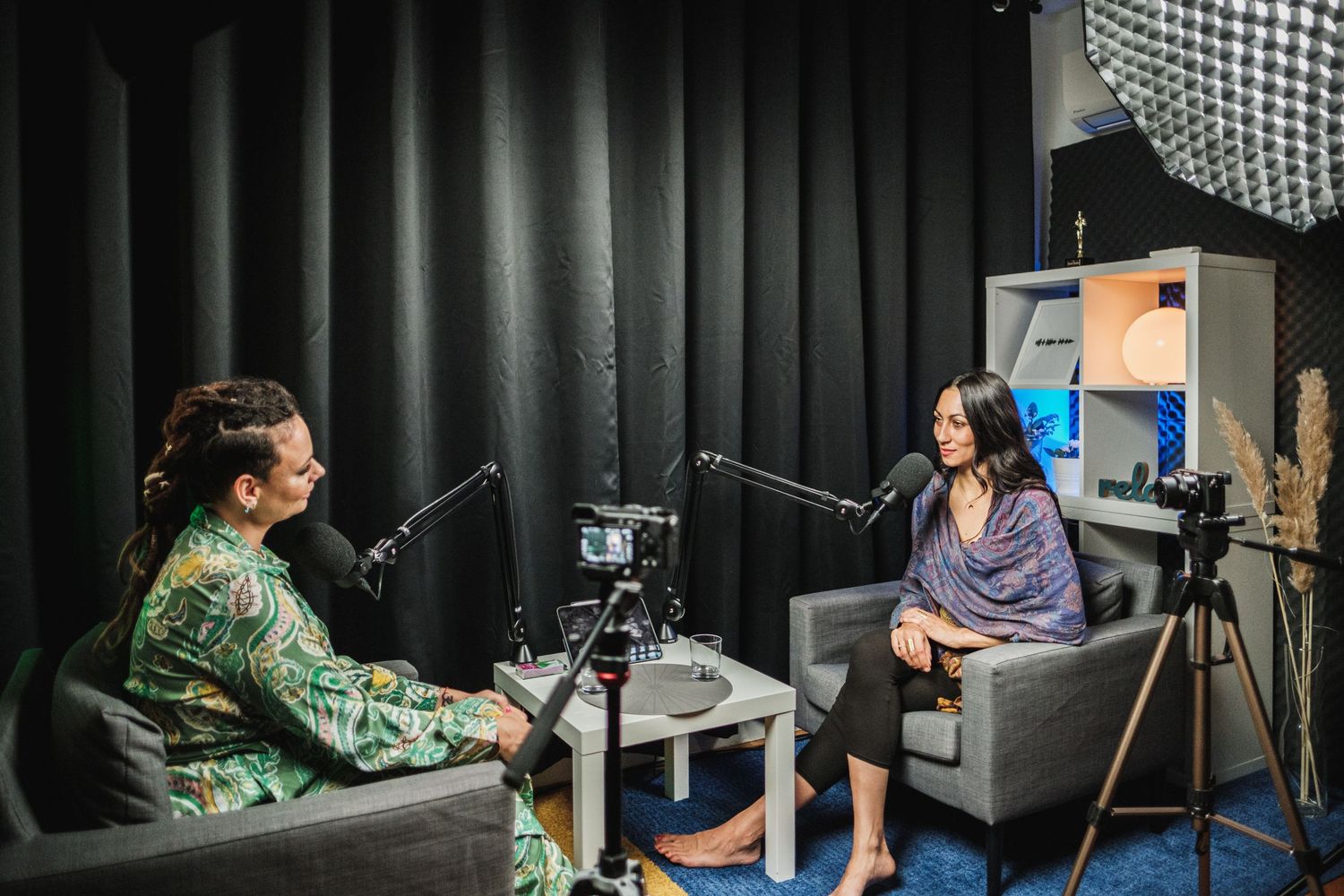 Professional podcast recording session between two hosts in modern studio with dark backdrop.