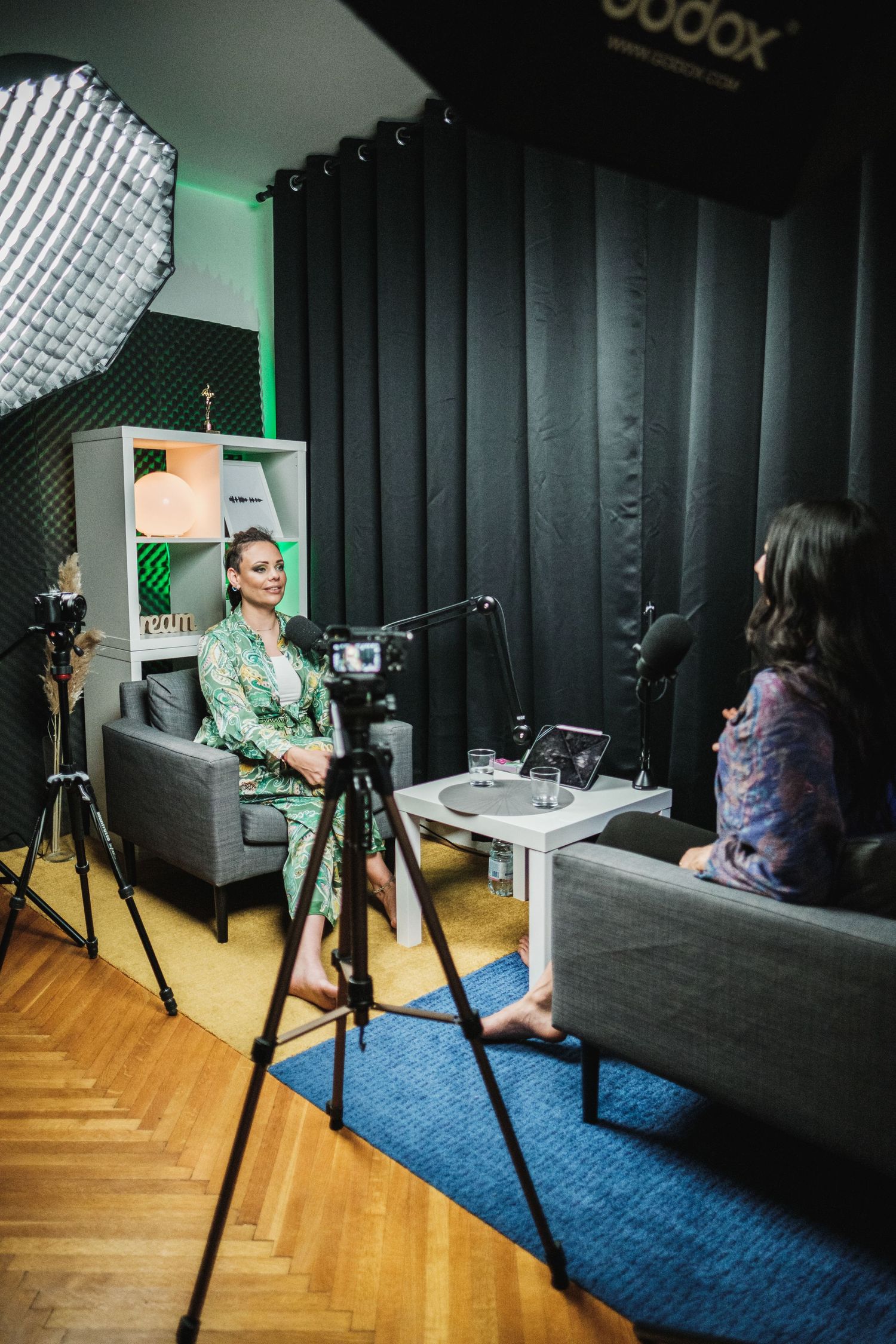 Behind-the-scenes view of podcast recording session with professional lighting and studio equipment.
