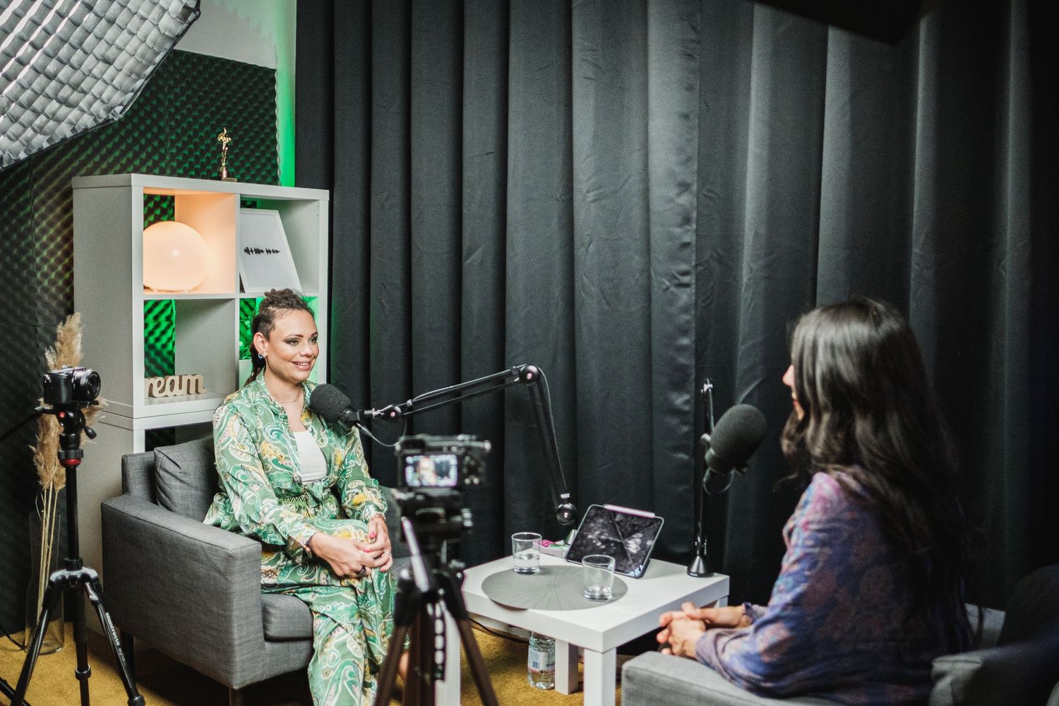 Two content creators engage in conversation during podcast recording in professional studio environment.