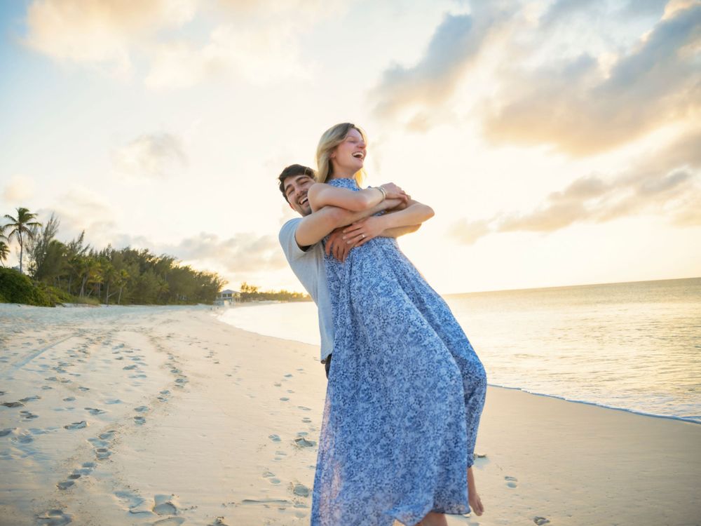 Romantic couple enjoying sunset on a tropical beach with palm trees.
