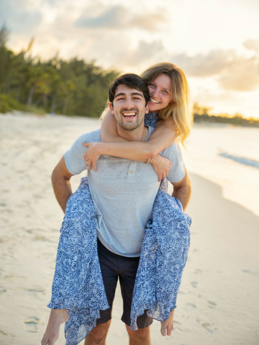 Playful couple having fun together on a sunny beach at sunset.