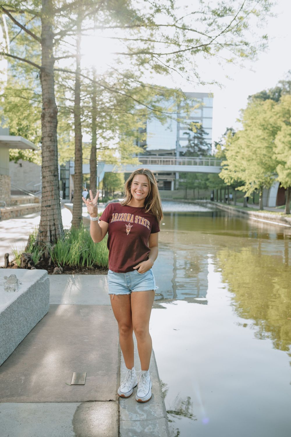 A casual outdoor photo on a university campus walkway near a reflecting pool on a sunny day.
