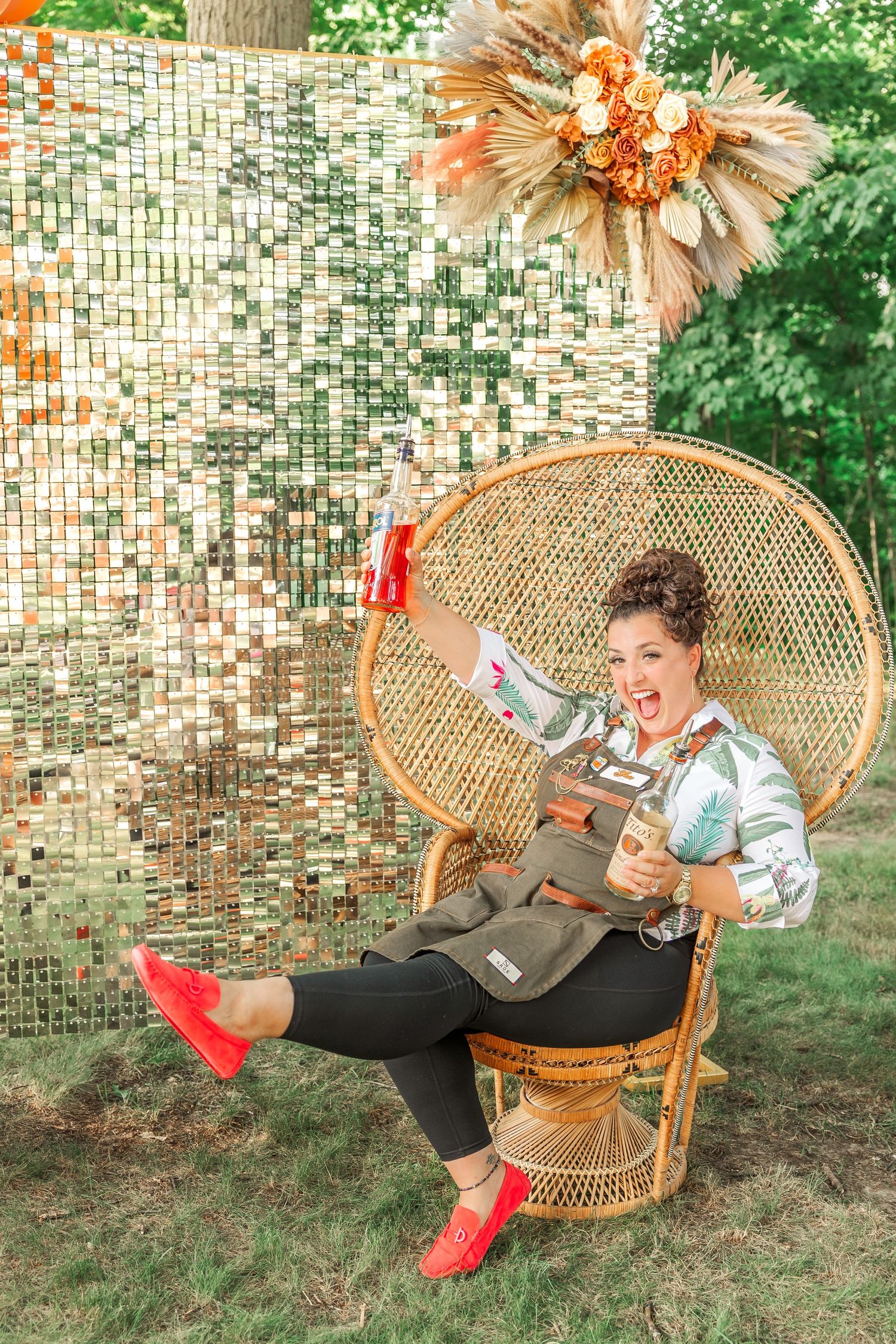 Playful pose in rattan peacock chair with silver metallic backdrop and orange decor.