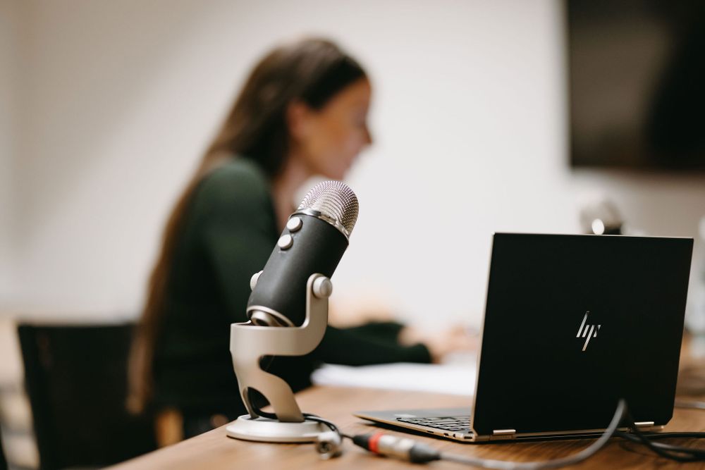 Person working at desk with laptop and microscope in professional setting.