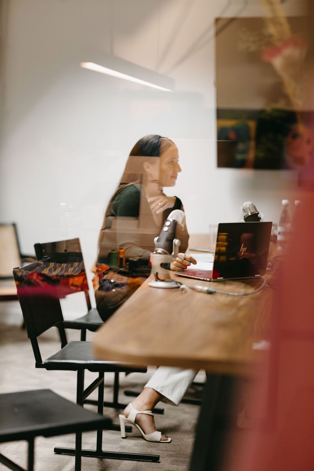 Side view of person working at desk through reflective glass surface.