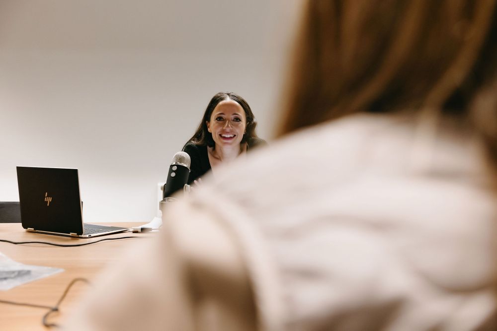 Professional laughing during a business meeting while seated at desk with laptop.