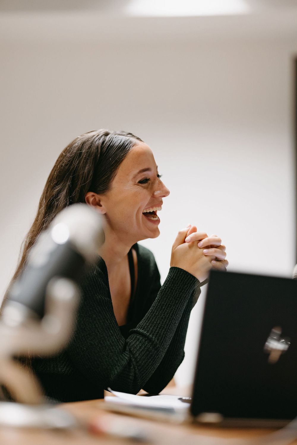 Professional expressing joy during office meeting with laptop.