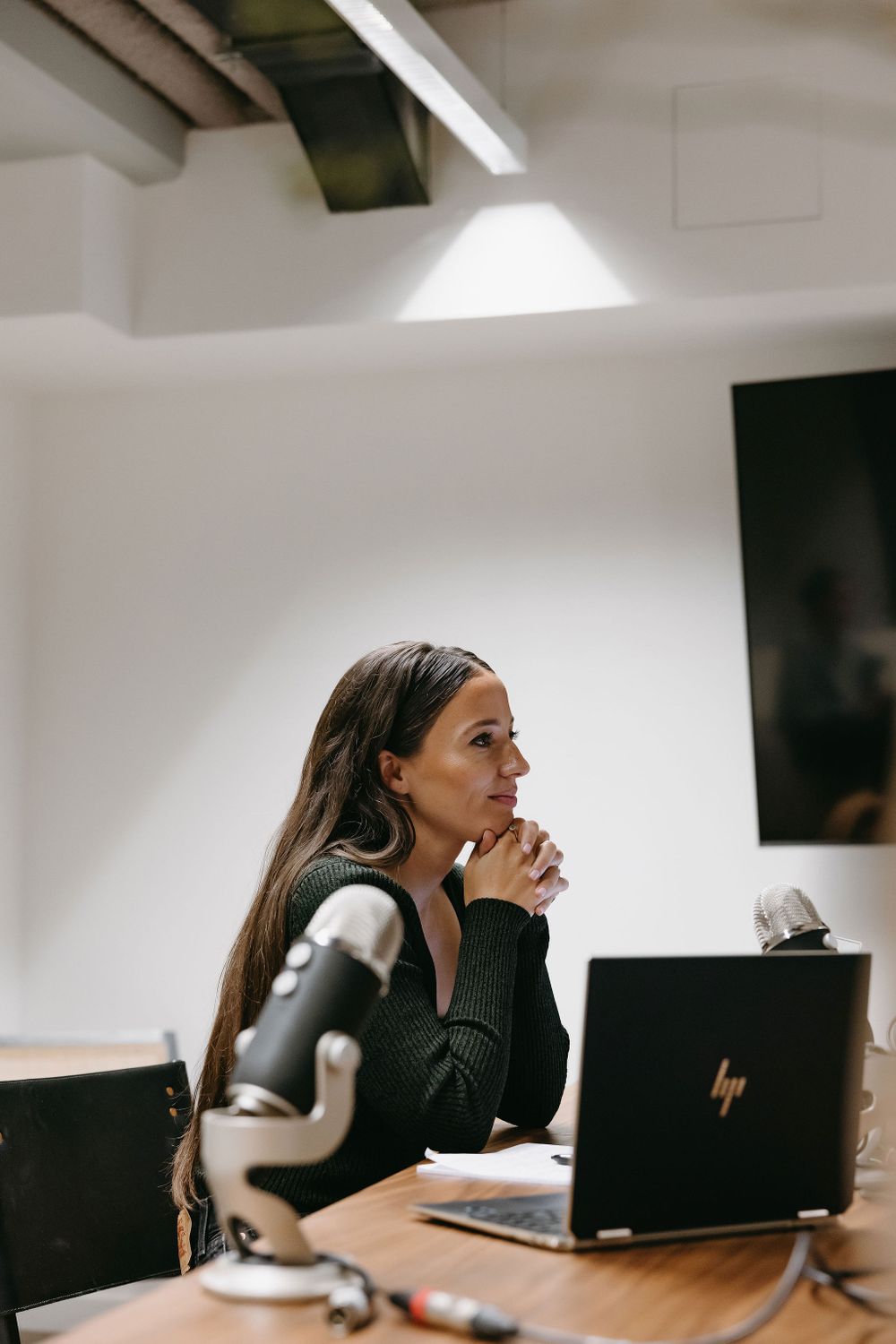 Professional in dark sweater contemplating during business meeting.