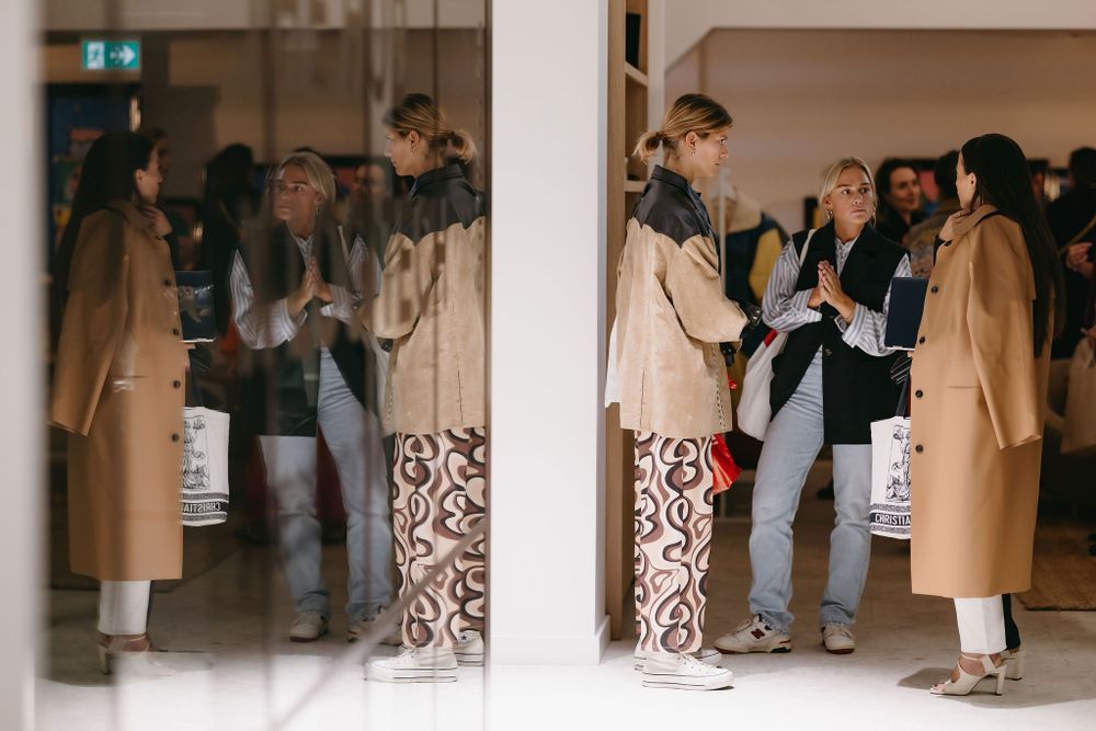 Group of people gathered in modern hallway wearing winter coats.