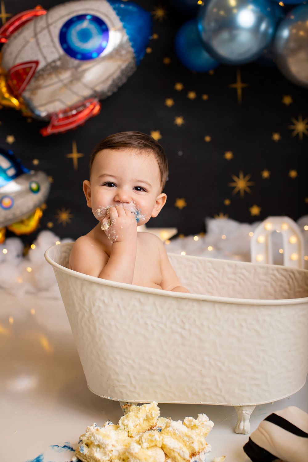 Baby cake smash photo with space themed decorations and tiny bathtub prop.