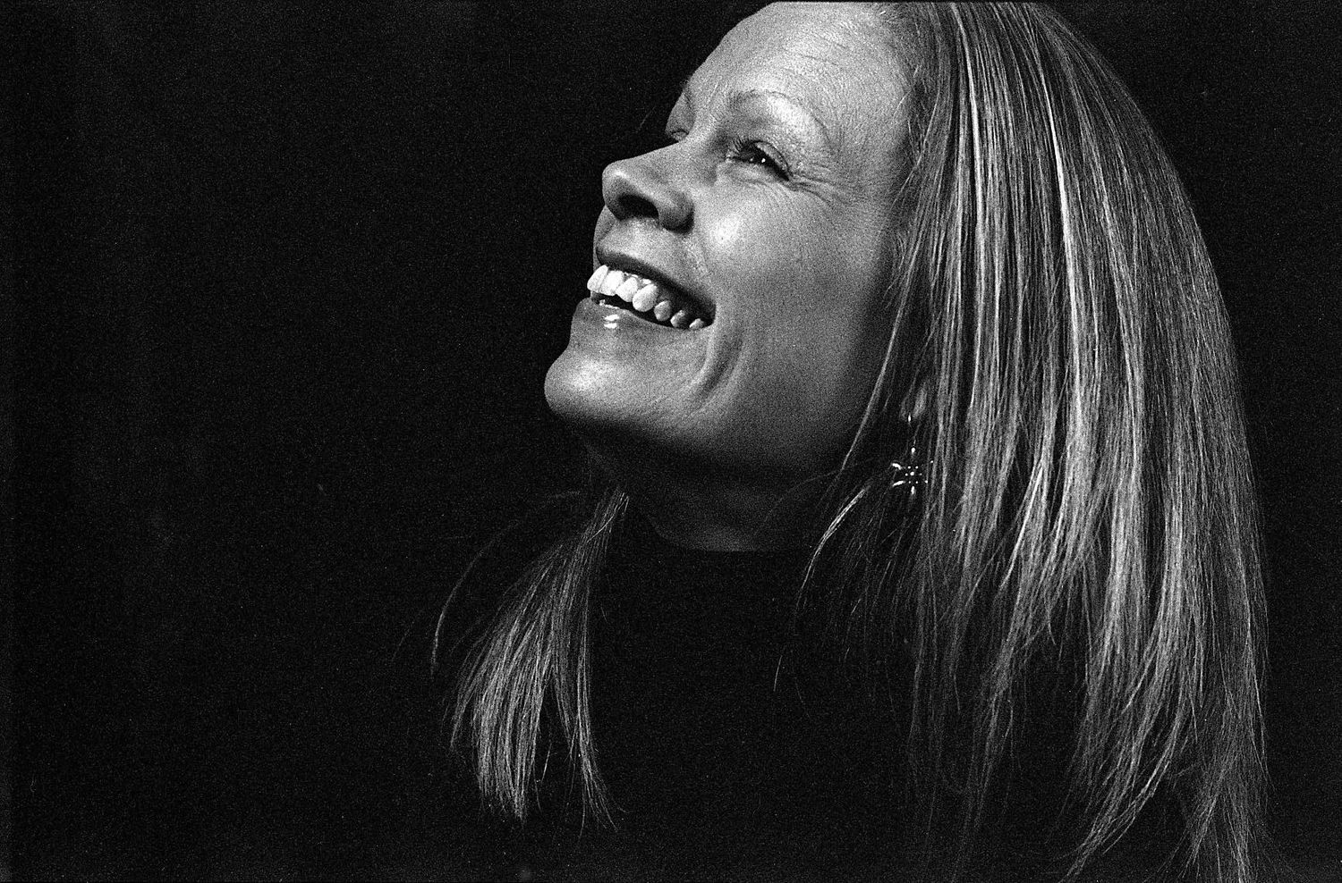 Black and white portrait capturing joyful laughter against dark background.