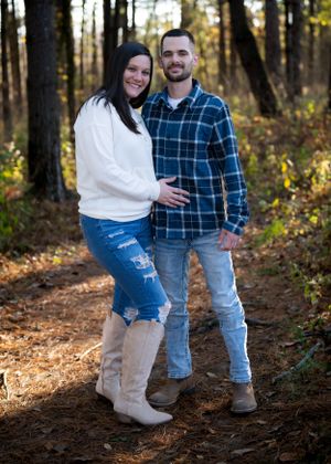 Couple in casual wear posing together on forest trail during fall season.
