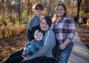 A family group poses on a path surrounded by fall foliage.