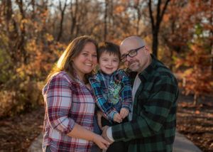 A family shares a warm embrace against a backdrop of autumn colors.