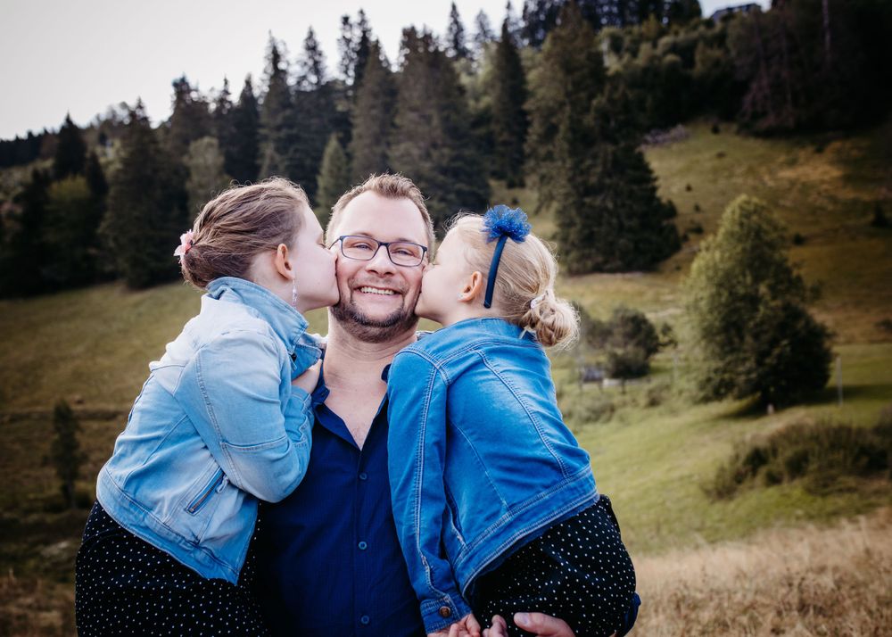 Sweet family moment captured in a mountain meadow with pine trees in background.