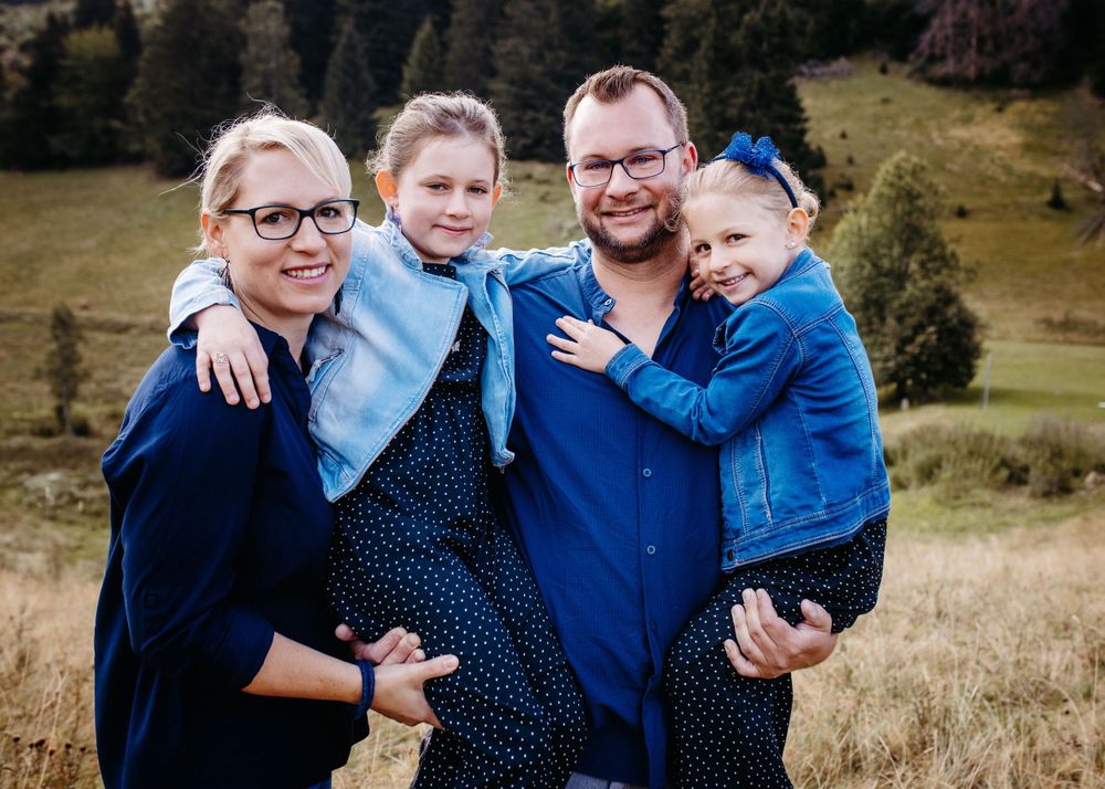 Family group photo in coordinating blue outfits against mountain landscape.
