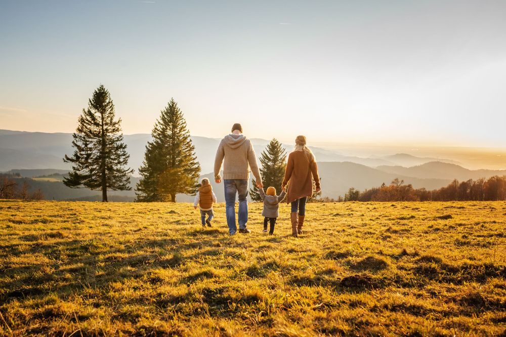 Family walking together on a hilltop during sunset with mountains in the background.
