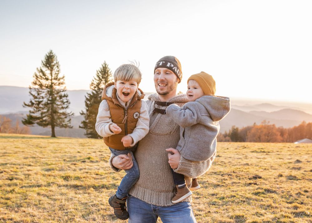 A joyful outdoor family moment in a sunlit mountain meadow during fall.