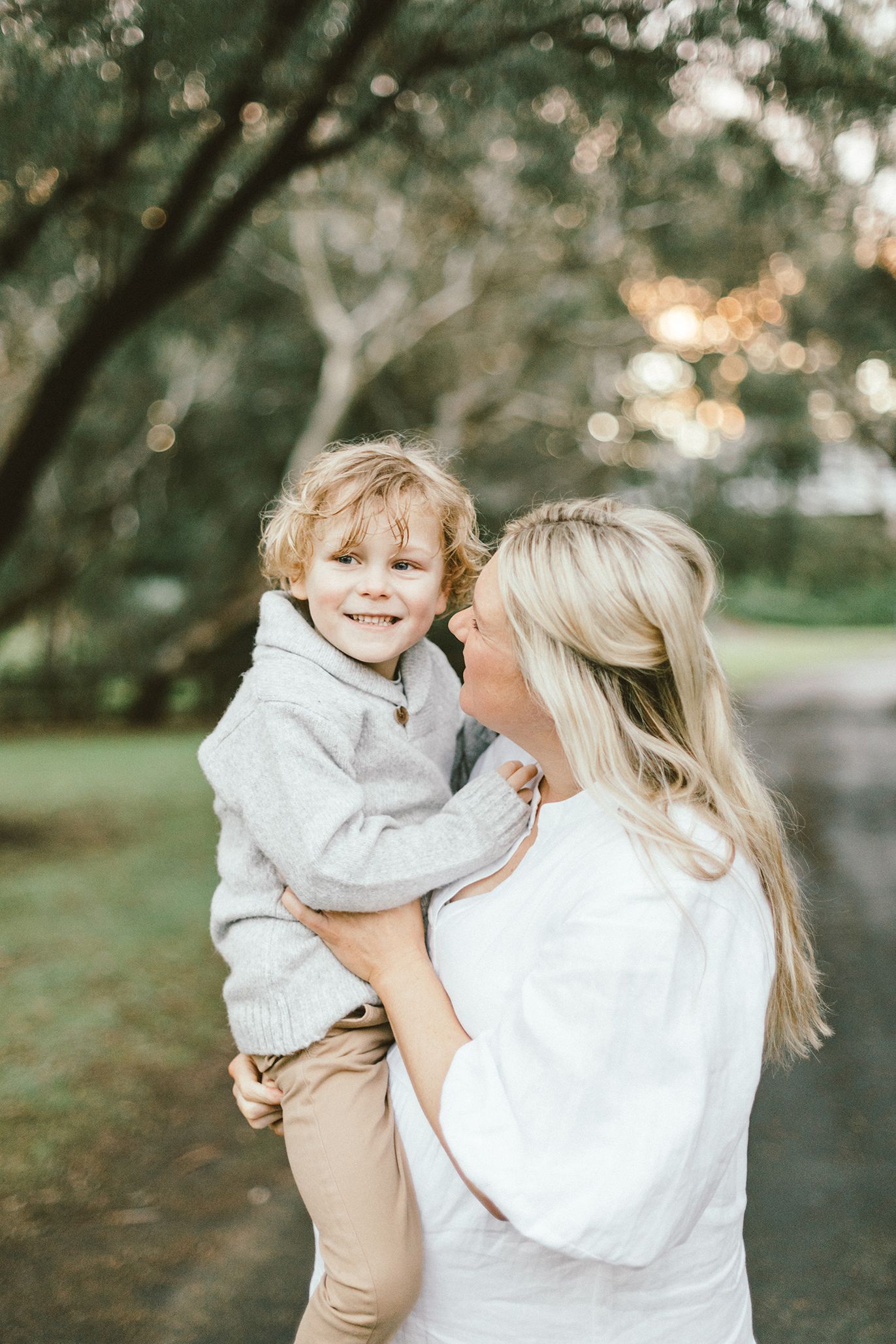 A joyful mother-child embrace in a serene park setting at dusk.
