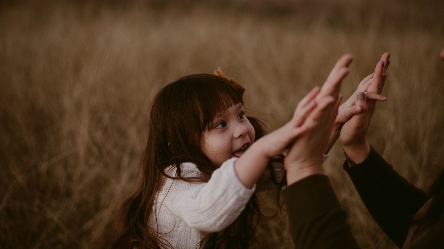 Close-up of hands reaching up toward sky in warm lighting.