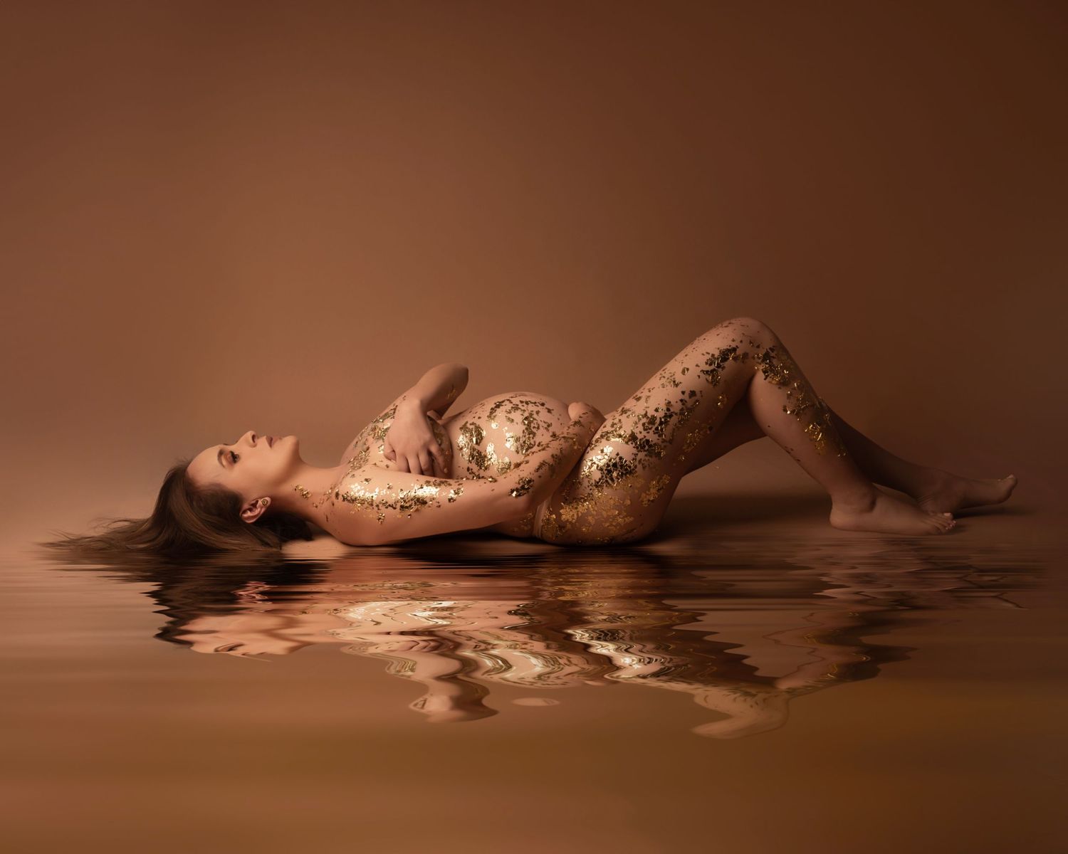 Artistic portrait with sparkly bodysuit and reflection in water against brown background.