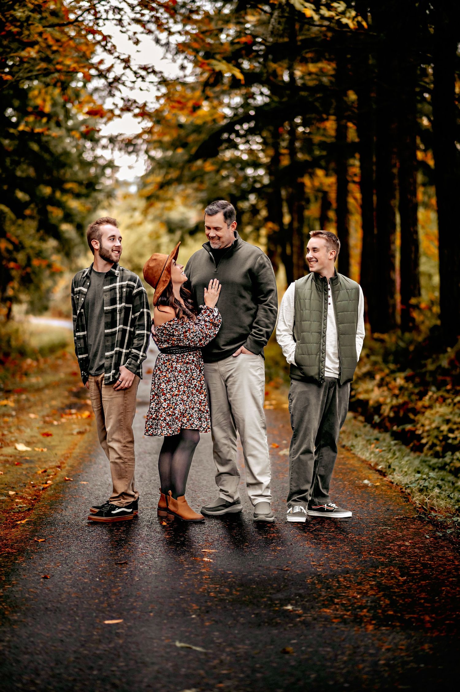 Family walking together on a tree-lined autumn path wearing casual clothing.