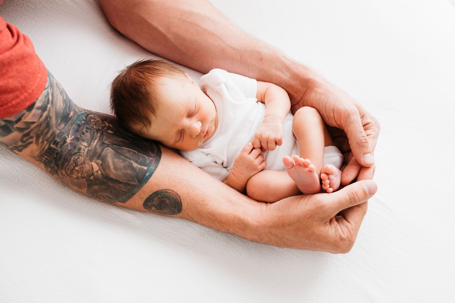 Newborn baby sleeping wrapped in dad's arms in Santa Fe, NM by Blooming Desert Photography.