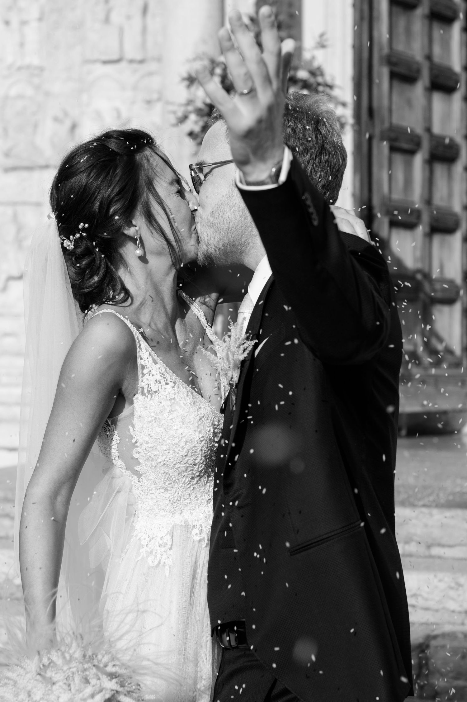 Black and white wedding photo of a couple celebrating with confetti in a romantic moment.