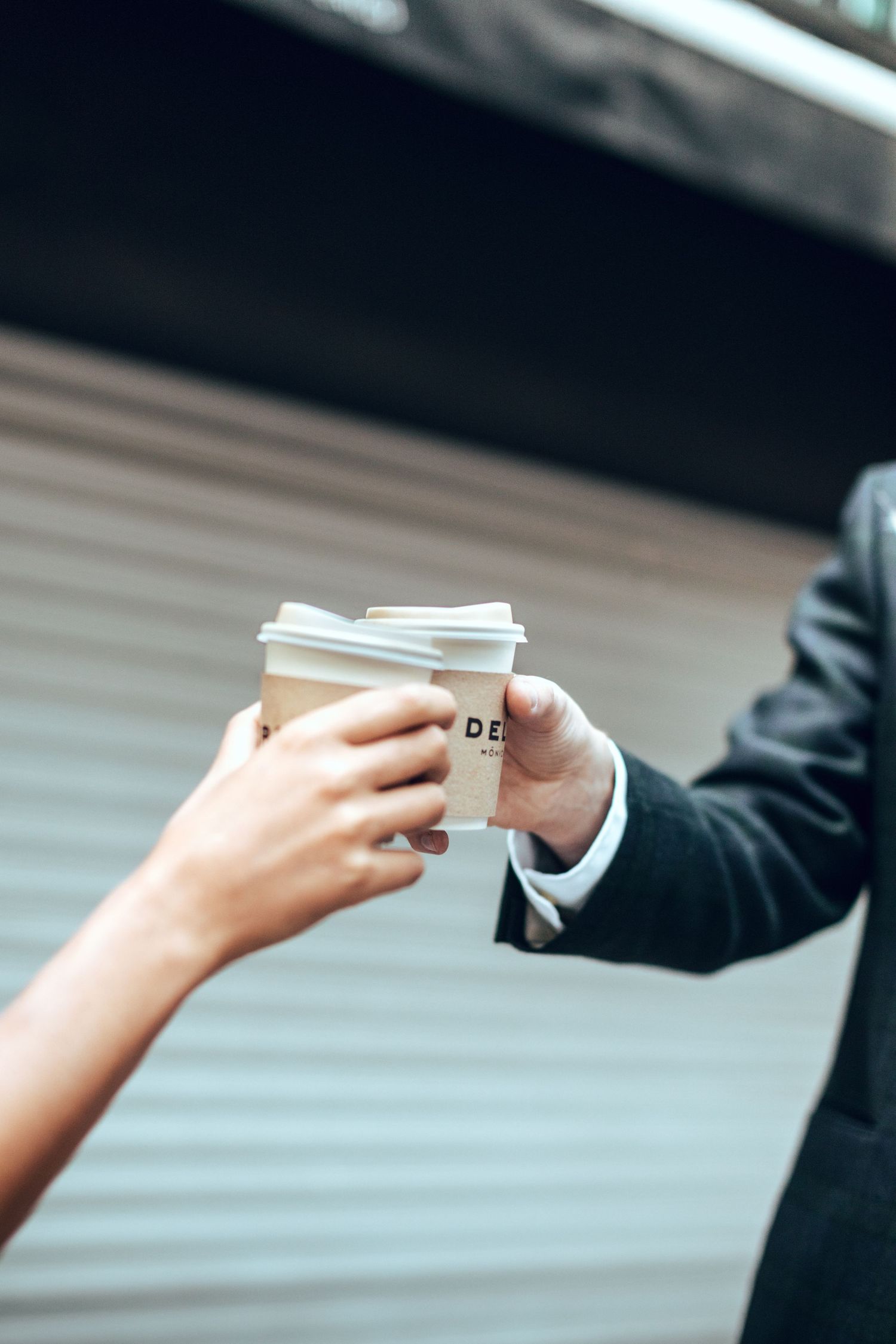 Close-up shot of hands exchanging coffee cups in a romantic moment.