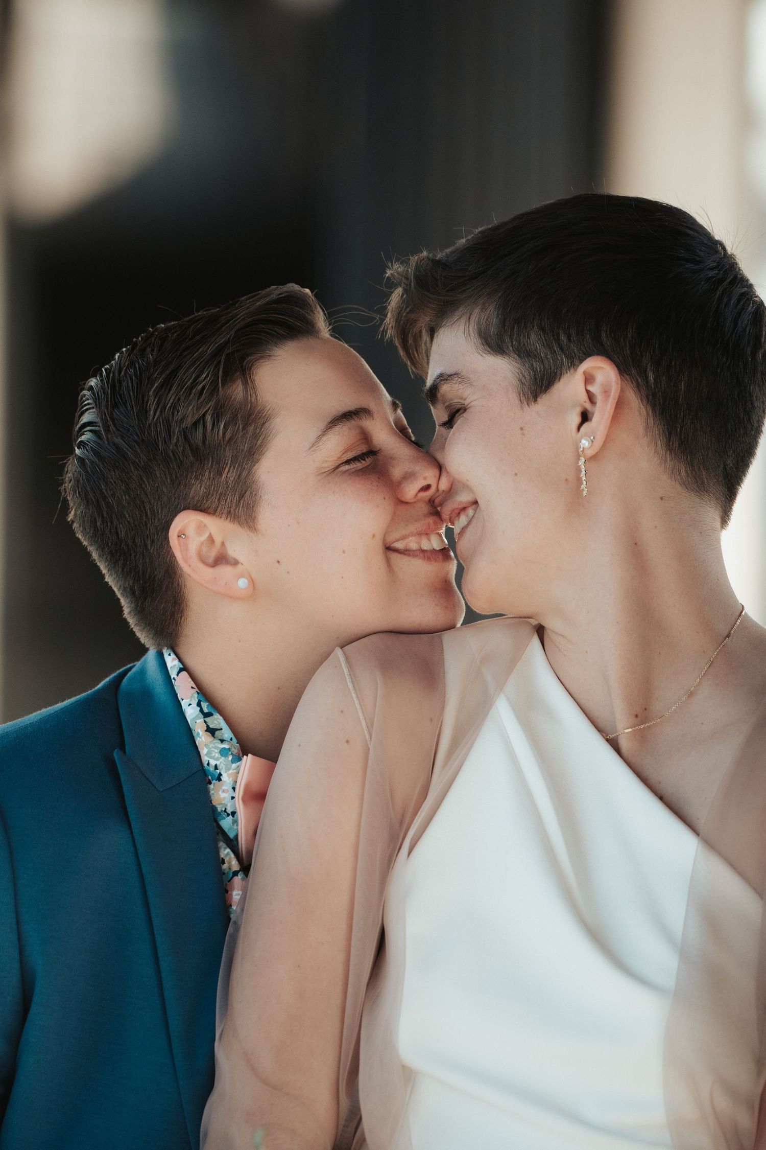 A newlywed couple leans into each other for a close up, noses touching.