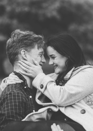 An intimate black and white portrait of a couple sharing a tender moment outdoors.