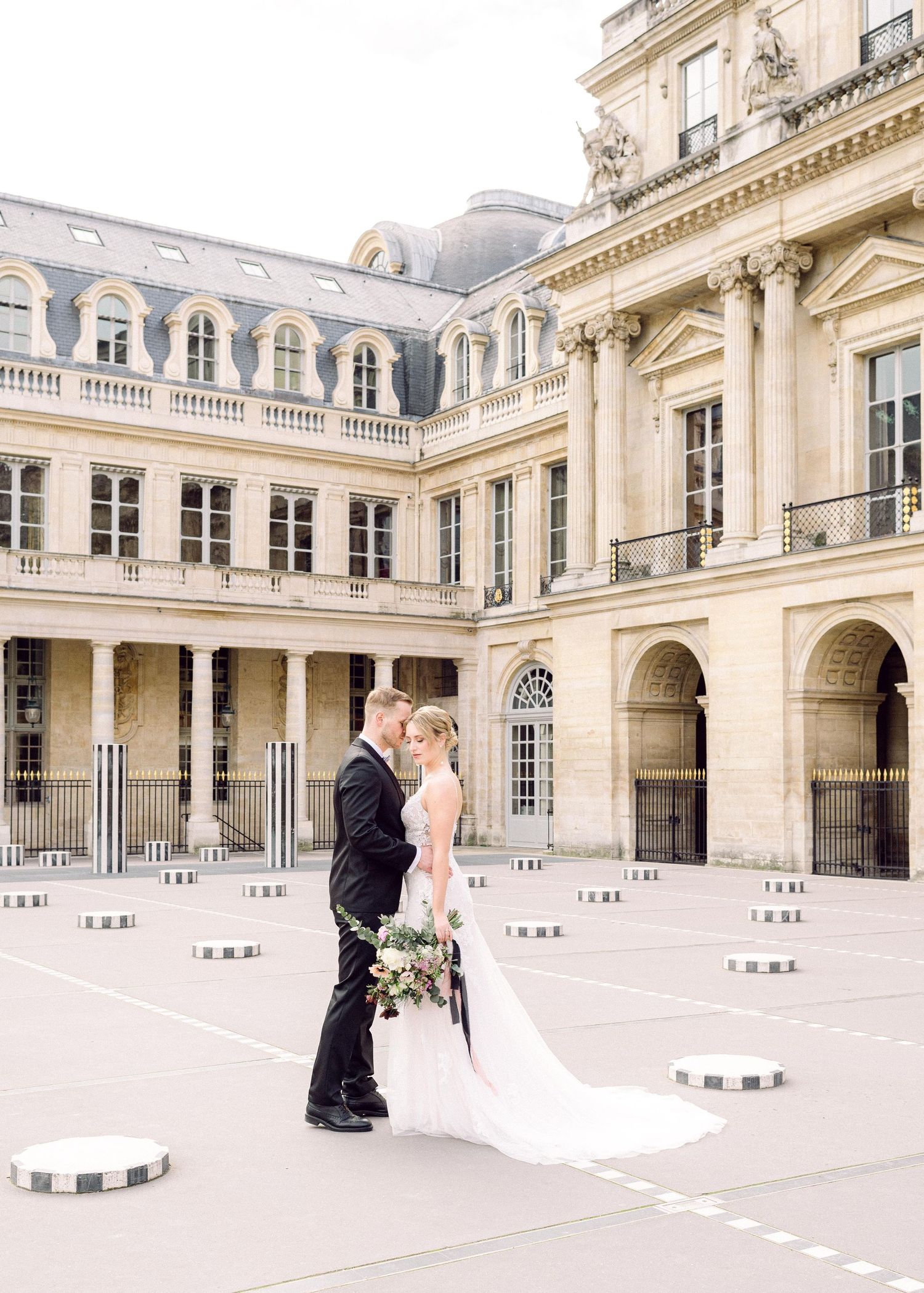 A romantic wedding photo session in front of a grand historic French Neoclassical building with ornate columns and ballistrades.