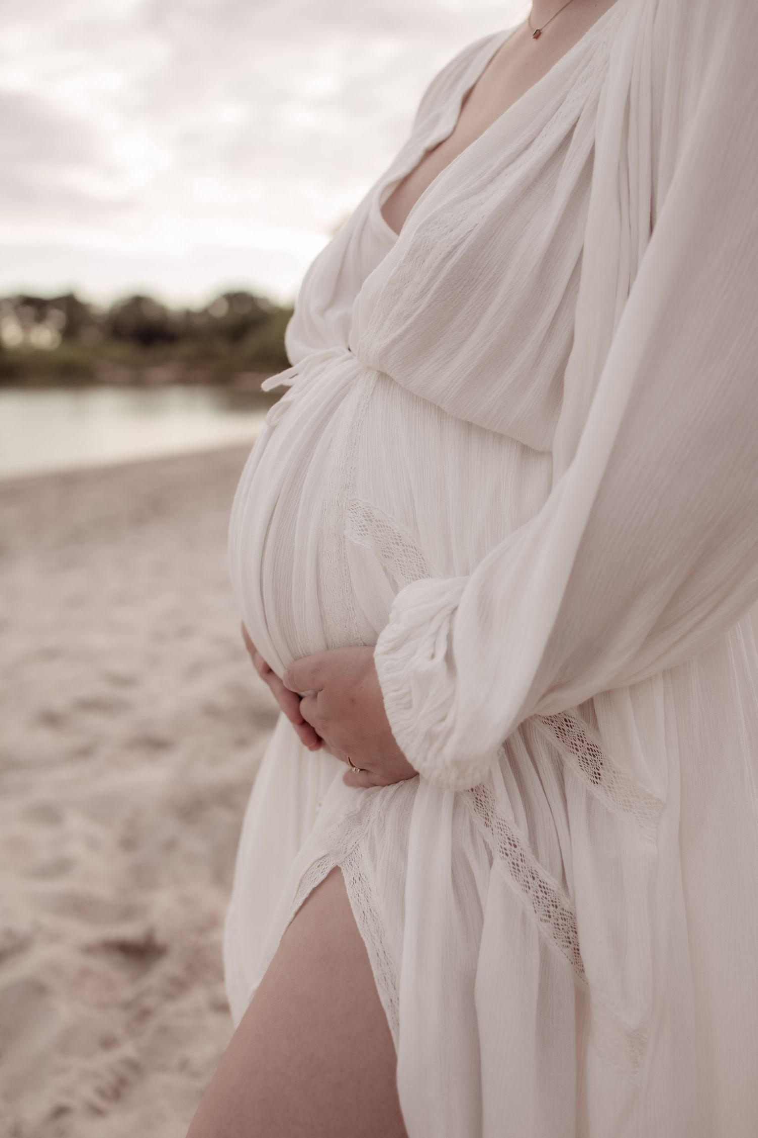 Zwangere vrouw met handen op buik in natuurlijk decor bij Helmond
Lifestyle zwangerschapsfoto met liefdevolle blik naar buik