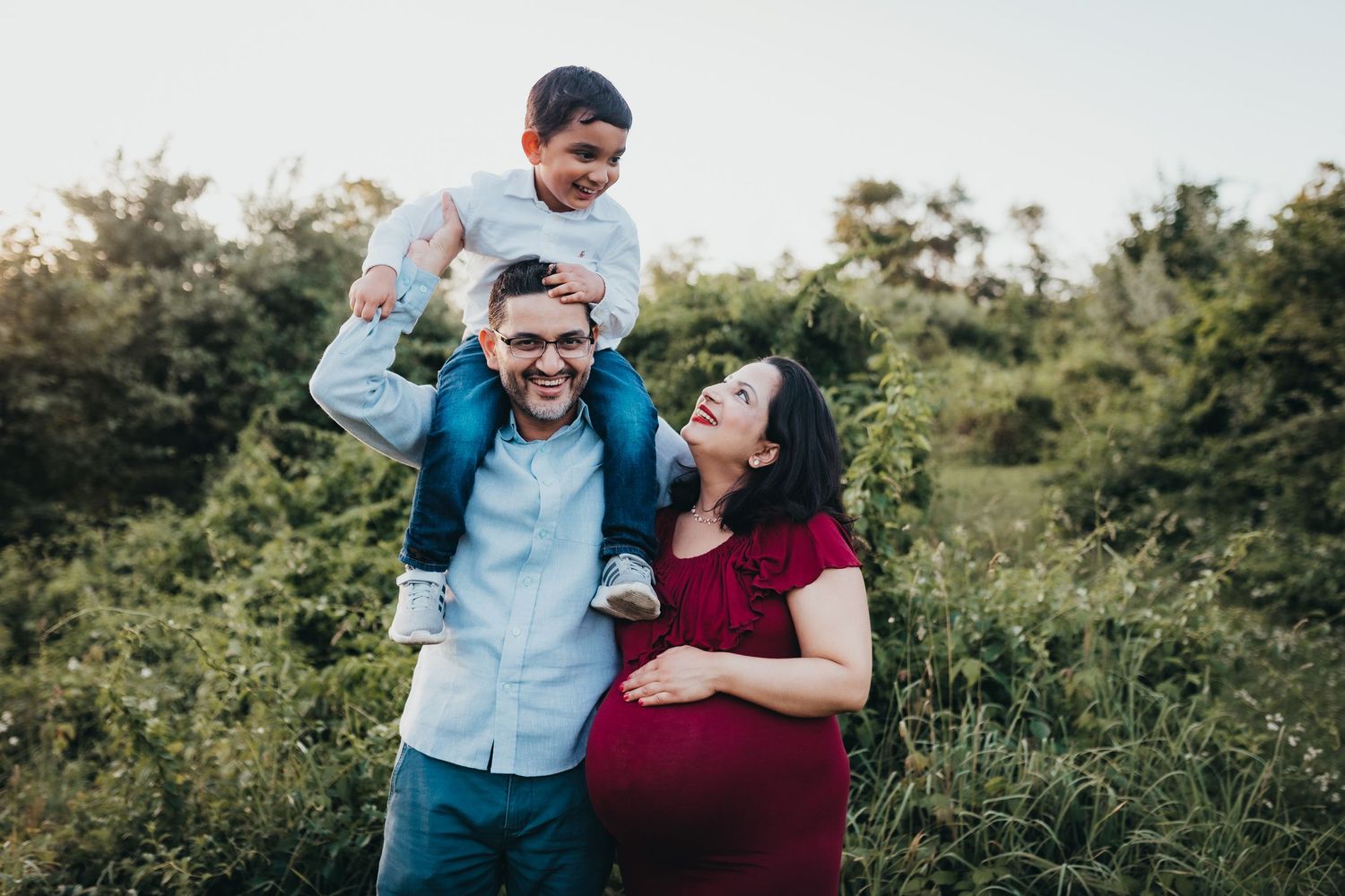 Family enjoying playful outdoor moments together in a green field.