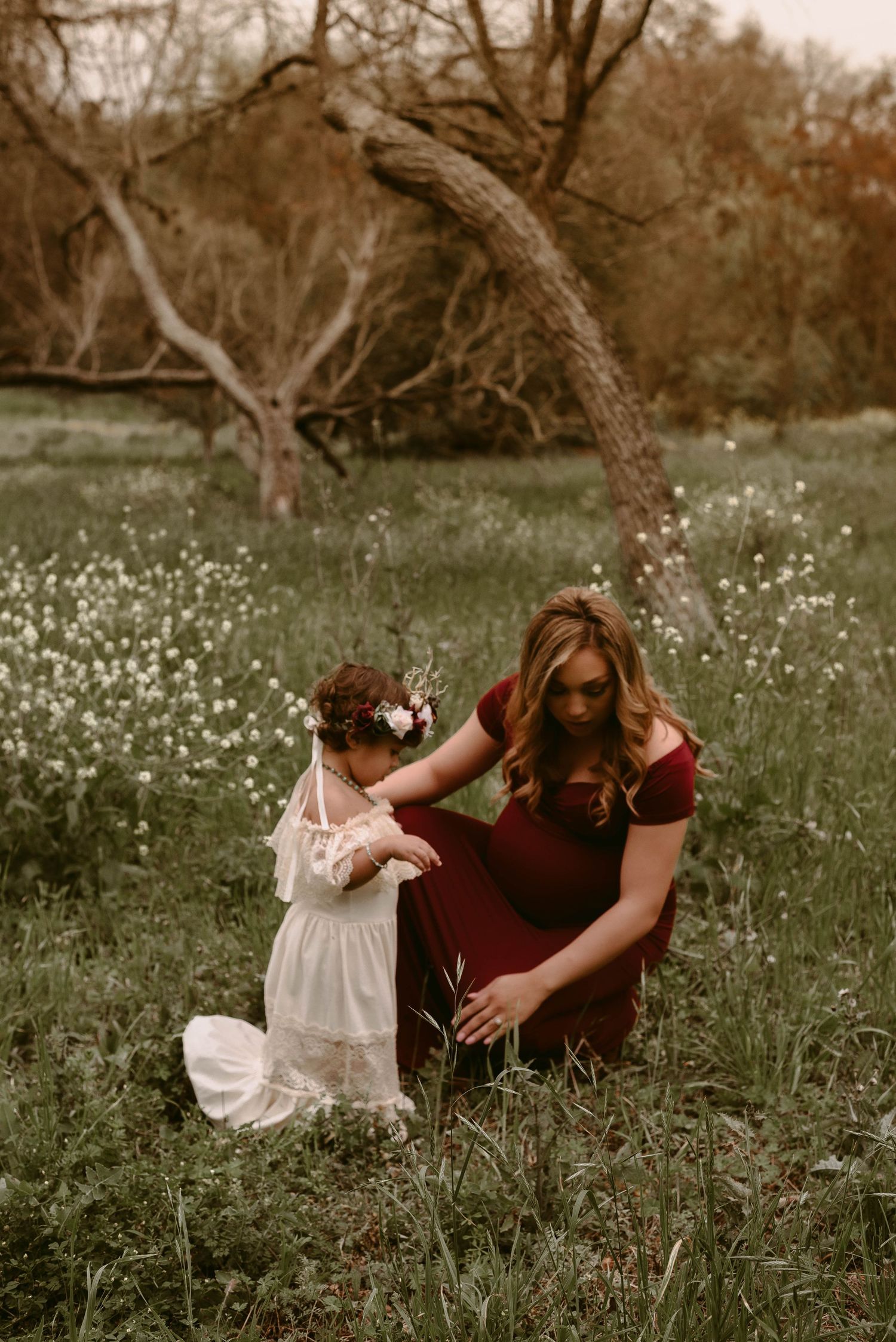 Sweet interaction between parent and child under a curved tree branch.