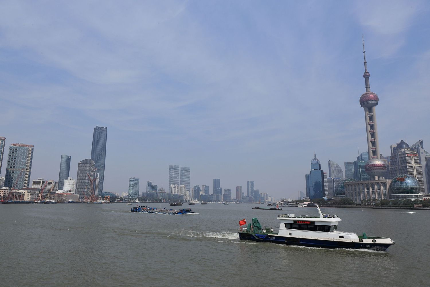 Boat cruising past Shanghai's iconic Pudong skyline and Oriental Pearl Tower.